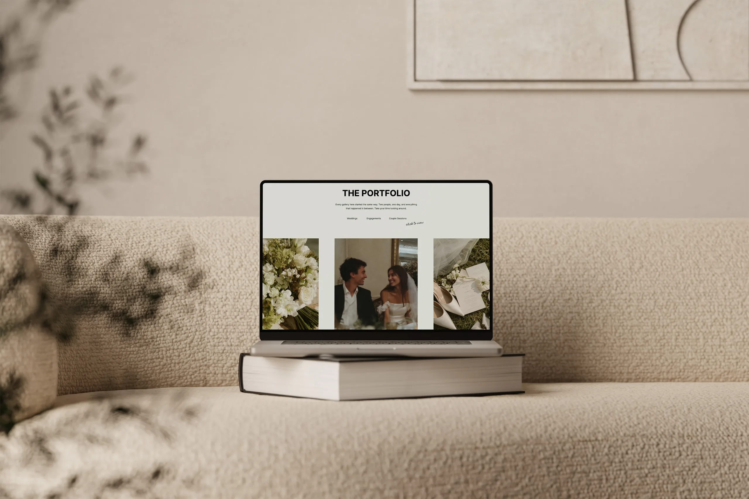 Laptop on a sofa displays a portfolio website in a softly lit neutral room.
