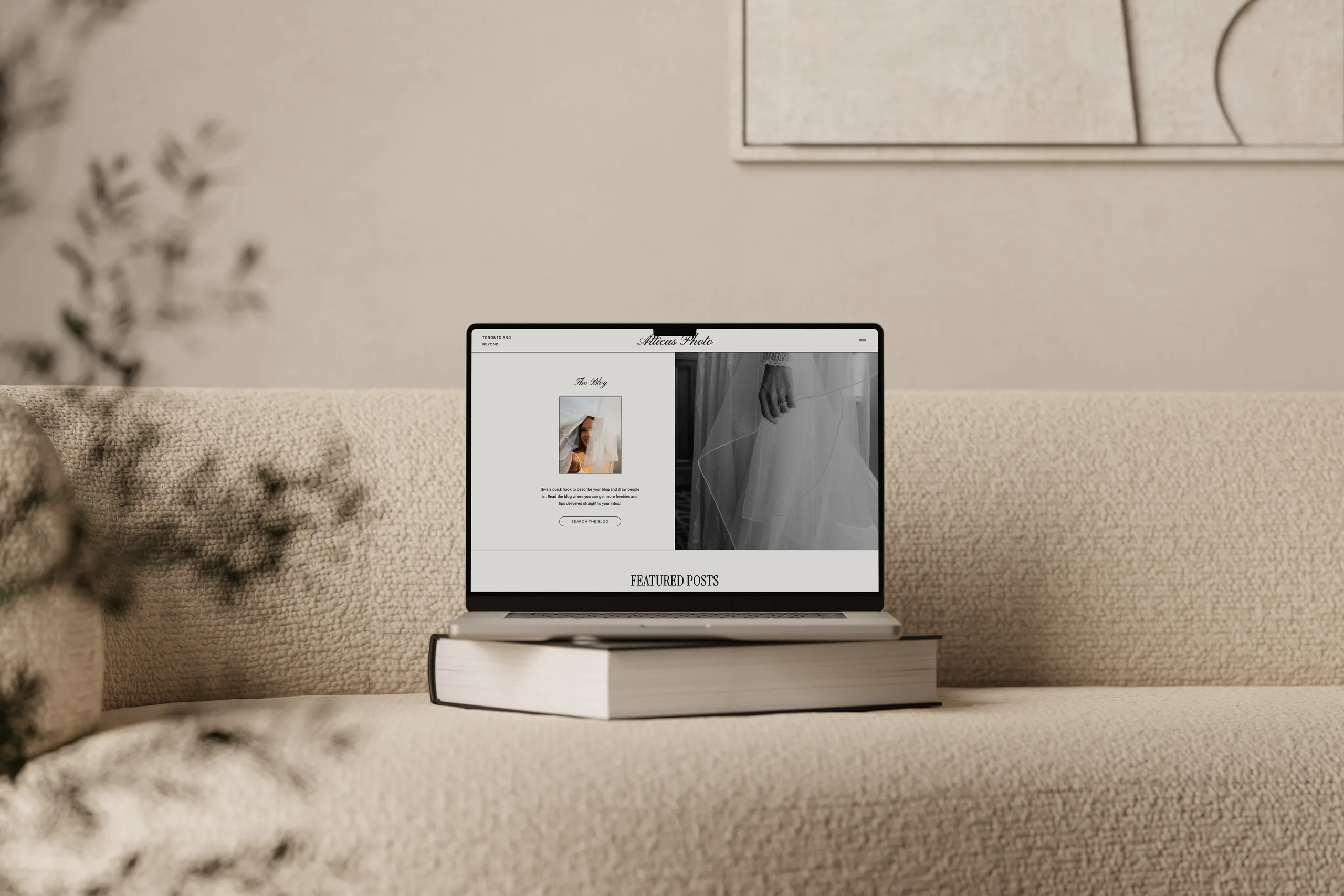 Laptop on stacked books displays a website layout on a beige sofa. — how to launch a showit website